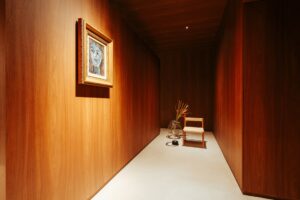 Corredor em marcenaria com quadro retrato e composição de cadeira e vaso no ambiente ATO_26, CasaCor RS 2026