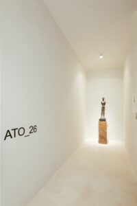 Identidade visual do ambiente ATO_26 na parede de entrada, com escultura em bronze ao fundo, CasaCor RS 2026