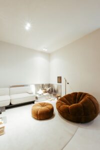 Canto do living do ambiente ATO_26 com sofá, poltrona em bouclé e bancada em aço inox, CasaCor RS 2026