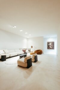 Living do ambiente ATO_26 com sofá, poltronas e obra de arte ao fundo, piso contínuo em Chukum, CasaCor RS 2026