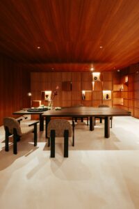 Mesa de jantar em madeira maciça e painel de marcenaria com nichos iluminados no ambiente ATO_26, CasaCor RS 2026