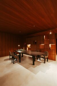Sala de jantar do ambiente ATO_26 com marcenaria em madeira escura e mesa maciça, piso contínuo em Chukum, CasaCor RS 2026