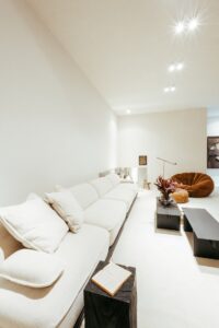 Detalhe do sofá e mesa lateral com livro no living do ambiente ATO_26, com poltrona em bouclé ao fundo, CasaCor RS 2026