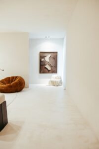 Passagem do ambiente ATO_26 com poltrona em bouclé e obra de arte ao fundo, piso contínuo em Chukum, CasaCor RS 2026