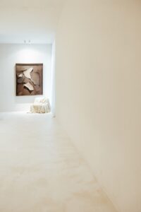 Corredor do ambiente ATO_26 com obra de arte emoldurada e peça coberta, piso contínuo em Chukum, CasaCor RS 2026
