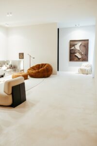 Vista em detalhe da sala de estar do ambiente ATO_26, com poltrona em bouclé, obra de arte e piso contínuo em Chukum, CasaCor RS 2026