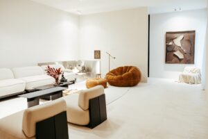 Sala de estar do ambiente ATO_26 com sofá branco, poltrona em bouclé e obra de arte ao fundo, piso contínuo em Chukum, CasaCor RS 2026