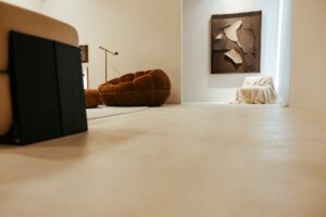 Poltrona e obra de arte no ambiente ATO_26, de Juarez Cruz, com piso contínuo em Chukum, CasaCor RS 2026