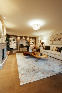 Vista ampla do ambiente Estar Entre Livros com iluminação aconchegante e piso em marcenaria geométrica, CasaCor RS 2026