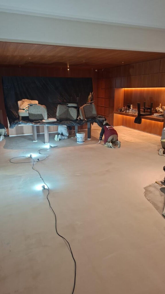 Vista do piso Chukum durante a montagem do ATO 26, com o mobiliário protegido e os elementos de madeira já instalados.